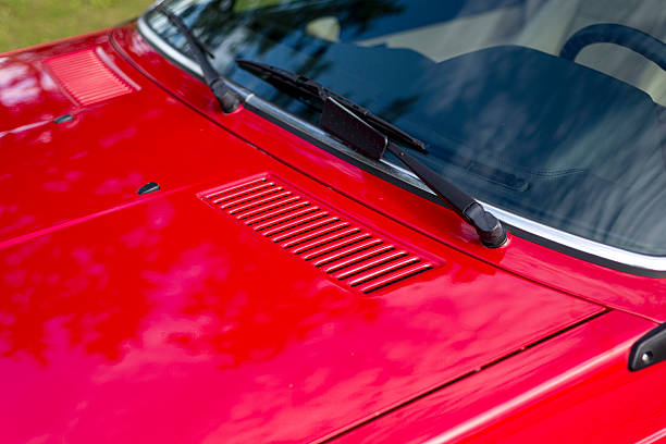 Side view to A pillar, front windshield and side door of a red sports car.