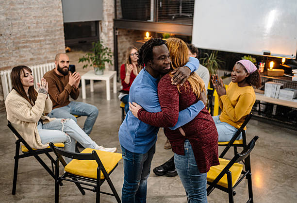 istock Group therapy participants embracing during support meeting 2251574634