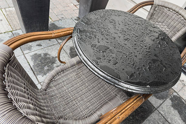 The surface of an empty table in a cafe wet from the rain. Selective focus.