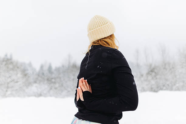 The unrecognisable woman standing in Reversed Prayed Pose outdoors in snowy winter day