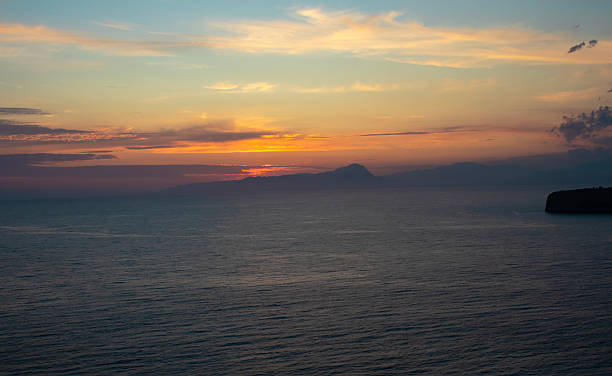 istock Sunset Over Ocean With Mountains on the Horizon and Clouds in the Sky During Evening Hours 2251583784