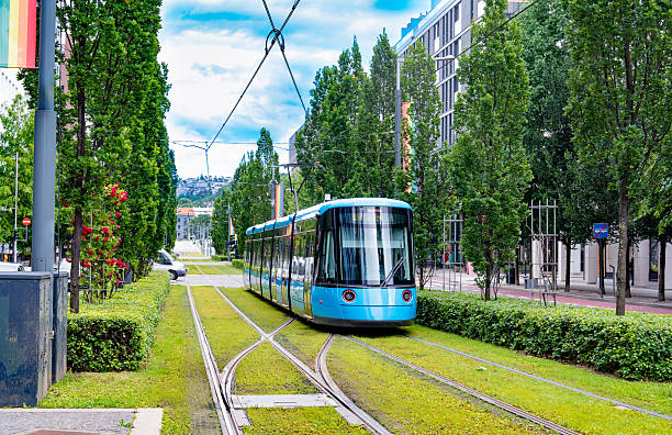 Oslo, Blue tram on Dronning Eufemias gate in Norway, showing modern buildings, trees and urban summer atmosphere.