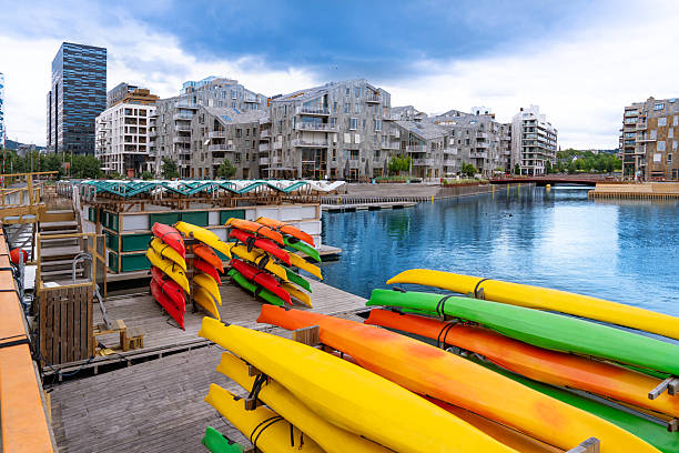 Oslo colorful kayaks stored at Bispevika waterfront in Norway, with modern residential buildings and calm water
