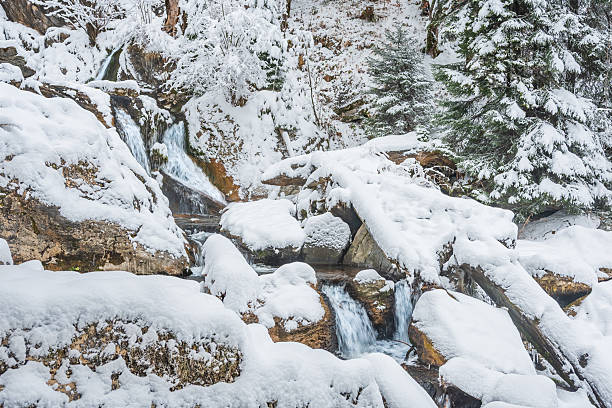 istock Mountain river in winter, water flows down the riverbed over snow-covered rocks. Winter landscape on a mountain hiking trail. 2251587231
