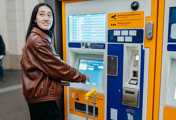 istock Young Woman Purchasing Train Ticket From Automated Ticket Machine At Station 2251588180