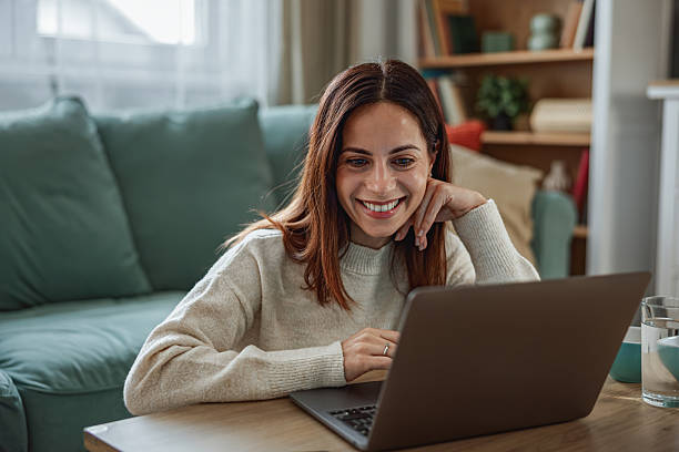 istock Young happy woman having a video call on laptop while sitting on sofa 2251589007