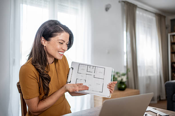 istock Woman architect showing floor plan during video call 2251590888