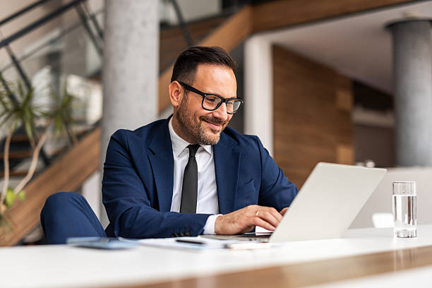 istock Businessman Smiling While Working on Laptop in Modern Office Environment 2251599278