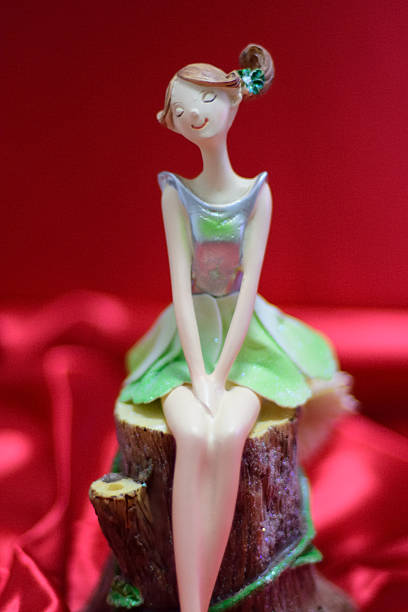 A whimsical figurine of a seated girl with a green dress on a red background.