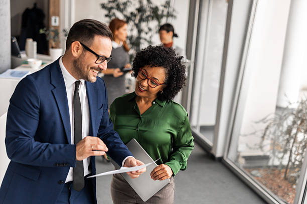 istock Smiling Coworkers Discuss Work While Reviewing Documents in an Office Setting 2251599976