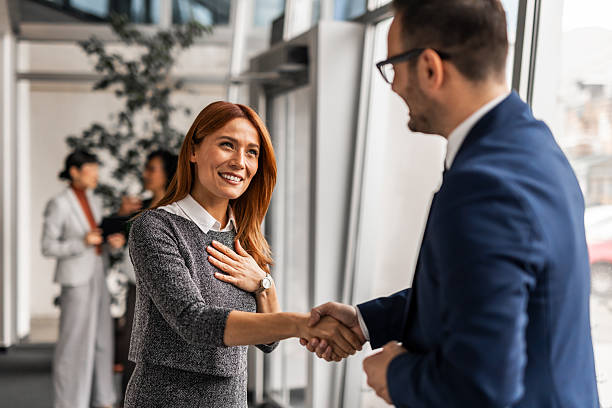 istock Colleagues Shaking Hands in Modern Office Environment 2251600357