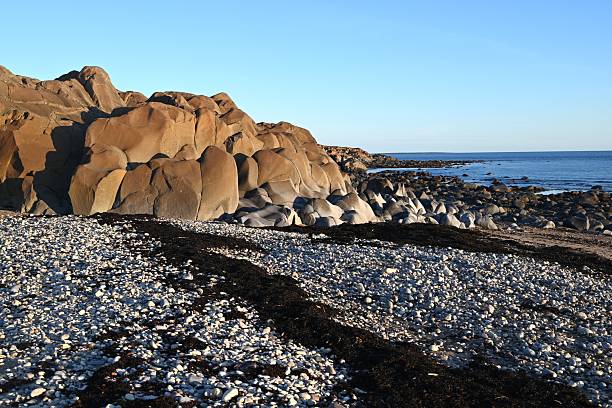 Seemingly watercolor painted rock formations rise over a beach with seaweed along Hudson Bay in the Churchill Wildlife Management Area, Manitoba.