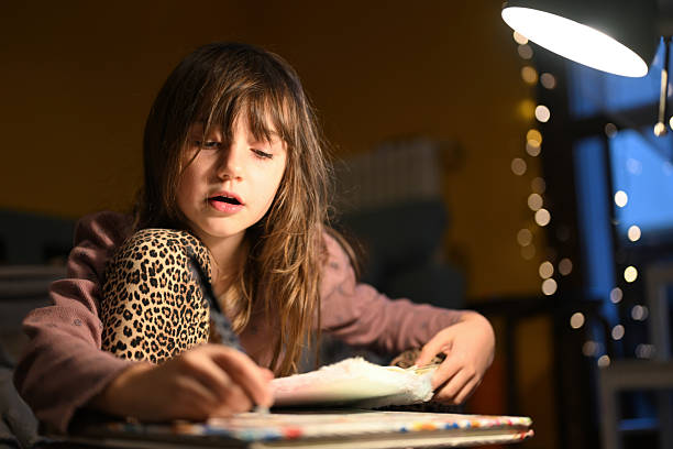 istock Girl concentrating under desk lamp doing homework at night 2251604612