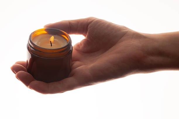 Cosmetic massage oil butter burning candle in woman hand isolated on white