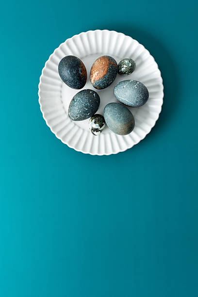 istock A collection of intricately decorated Easter eggs in various shades rests on a white plate against a soothing teal backdrop, perfect for spring festivities and family traditions 2251607341