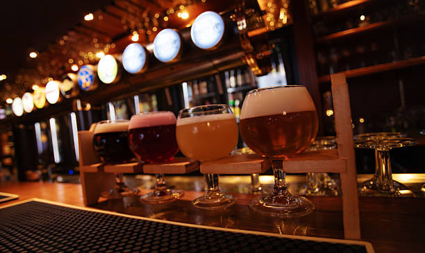 istock Glasses of assorted craft beers displayed on a bar counter inside a pub, with illuminated beer taps in the background. 2251614585