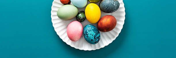 istock Festive, colorful eggs in various shades are neatly arranged on a decorative plate, symbolizing Easter traditions and spring celebrations with vibrant designs, banner 2251615517