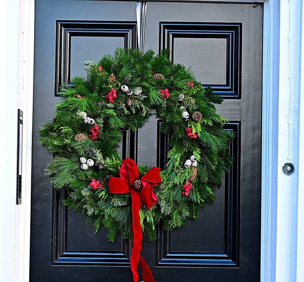 istock Festive holiday wreath with red bow on black door 2251619302