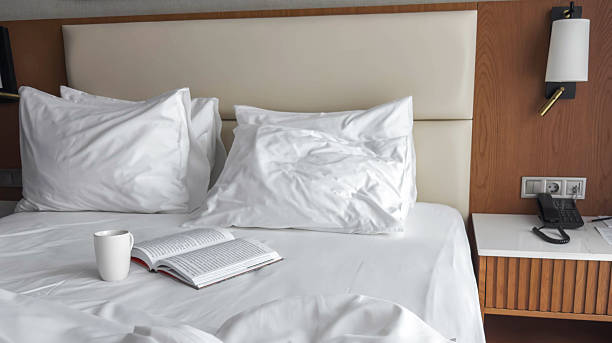 istock Cozy hotel bed with white pillows, soft bedding, open book and coffee cup creating a calm morning atmosphere in a modern room with warm wooden accents and gentle natural light 2251620561