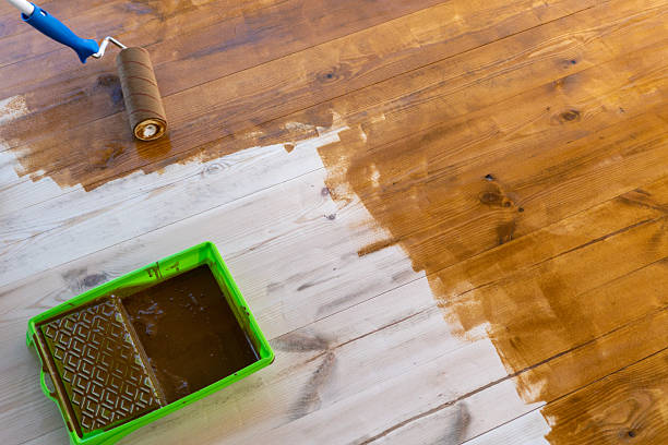 istock Wooden floor staining with paint roller and tray for home renovation project 2251622418