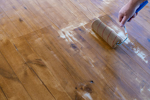 istock Hand applying varnish on wooden floor with roller for smooth finish 2251622457