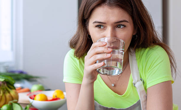 istock young woman drinking water at kitchen 2251624003
