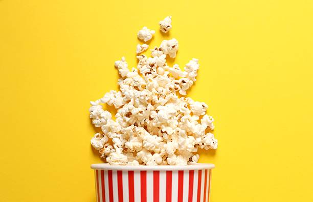 istock Delicious popcorn in a striped cardboard basket on a colored background 2251625519