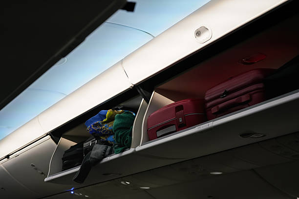 istock Airplane overhead locker with baggage suitcases, closeup detail 2251626645