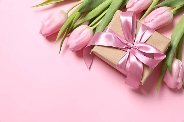 istock Beautiful pink tulips and craft gift on colored background 2251627163