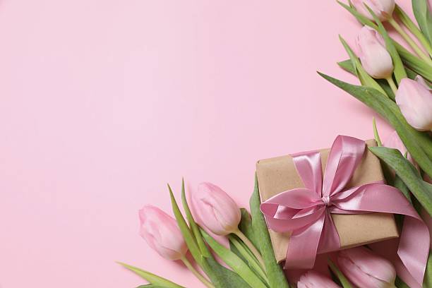 istock Beautiful pink tulips and craft gift on colored background 2251627164