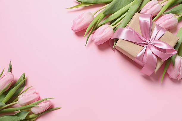 istock Beautiful pink tulips and craft gift on colored background 2251627165