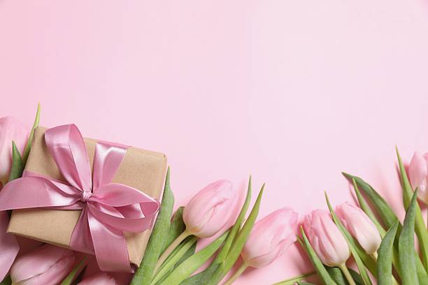 istock Beautiful pink tulips and craft gift on colored background 2251627181