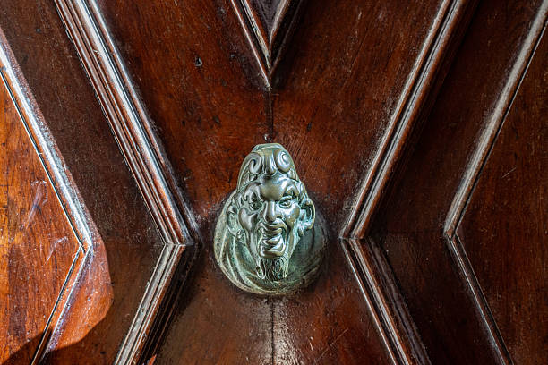 Antique door handle in the form of a demonic image with a ring in the mouth in gilding. High quality photo