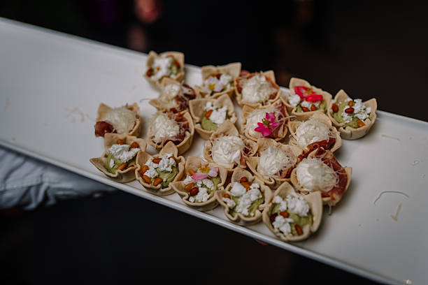 Gourmet appetizers arranged beautifully on a white platter, featuring delicate pastry shells filled with creamy cheese, fresh herbs, and vibrant edible flowers for an elegant dining experience