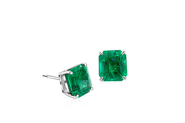A pair of vibrant emerald gemstone stud earrings showcased against a pristine white backdrop, highlighting their luxurious and classic design.
