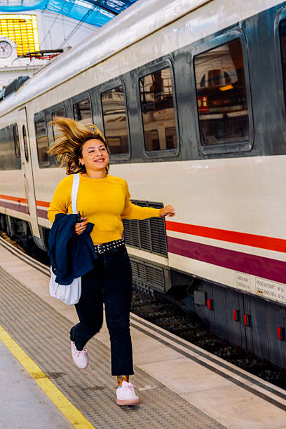 istock Young woman running to catch train at platform 2251642464