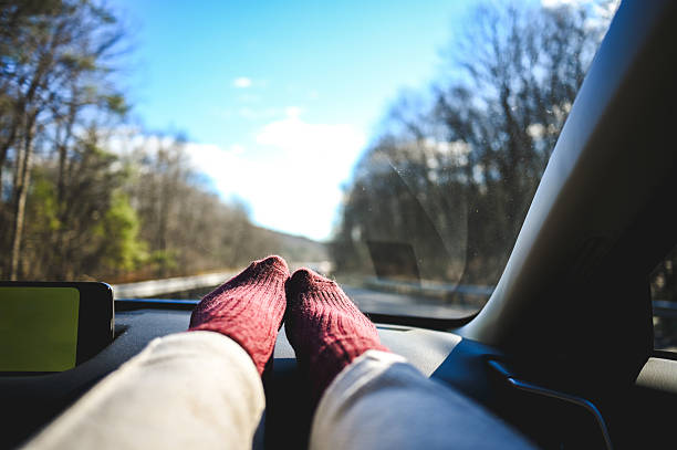 Passenger enjoying a relaxing road trip with feet up on the car dashboard