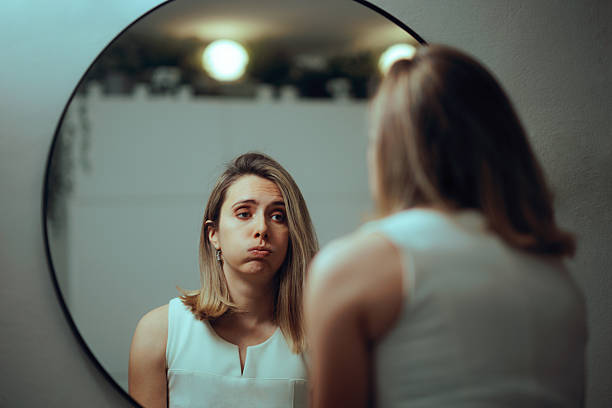 istock Unhappy Woman Looking in the Mirror Being Insecure 2251660774