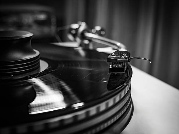 A close-up of a spinning vinyl record on a turntable, capturing the motion of grooves and the stylus. Classic analog music setup evokes nostalgia, creativity, and warm sound. Night mood.