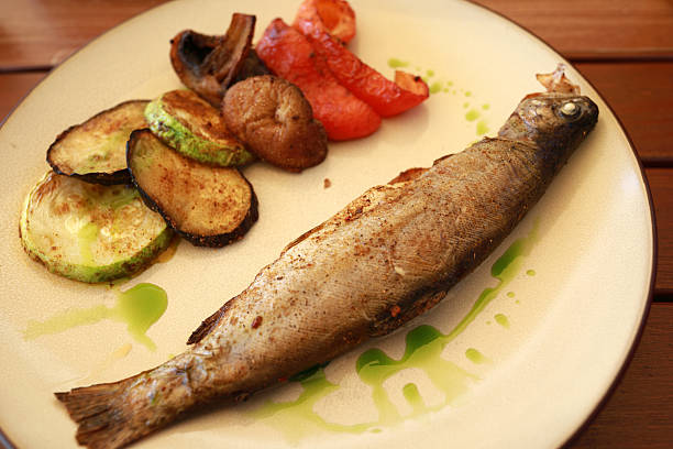 istock Cooked trout fish dish on plate with grilled vegetable and green sauce 2251664095