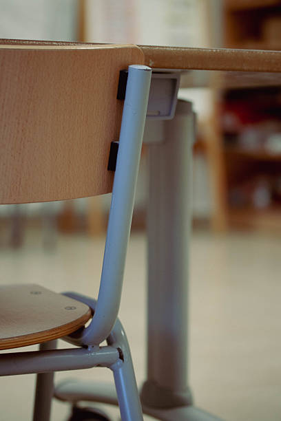A focused view of several desks and chairs positioned in a neat row within a classroom. The ambiance suggests a lively, welcoming, and educational environment for learning and growth.