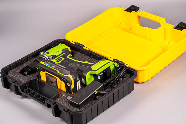 Cordless drill and accessories set in yellow case on gray background