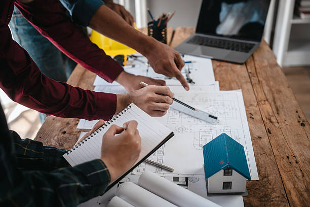 istock Two male engineers and a strong woman discuss blueprints and home design at a table. They work as a professional team, collaborating on construction projects with precision and expertise 2251669241