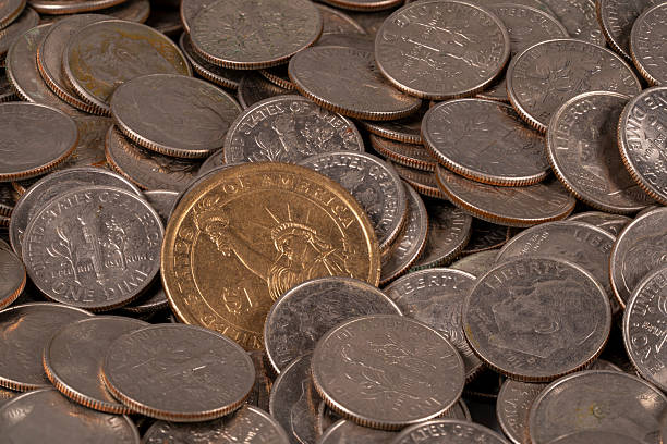 istock Coins scattered on a table with a golden dollar among them 2251669987