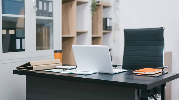 istock A modern office workspace with a black desk, documents, a coffee cup, and a laptop. The empty ergonomic chair and neat setup reflect professionalism, organization, and corporate productivity 2251676348