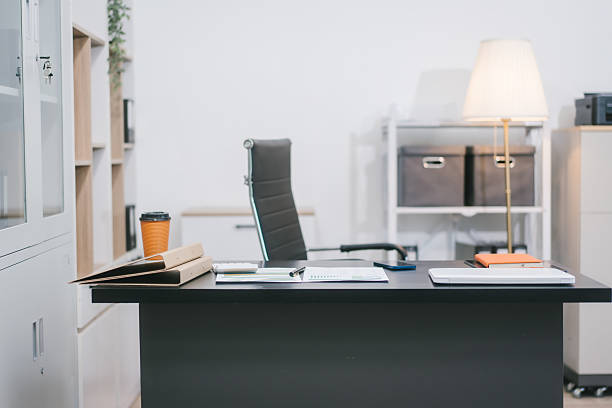 istock A modern office workspace with a black desk, documents, a coffee cup, and a laptop. The empty ergonomic chair and neat setup reflect professionalism, organization, and corporate productivity 2251676371