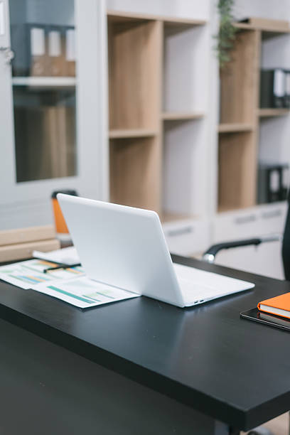 istock A modern office workspace with a black desk, documents, a coffee cup, and a laptop. The empty ergonomic chair and neat setup reflect professionalism, organization, and corporate productivity 2251676377