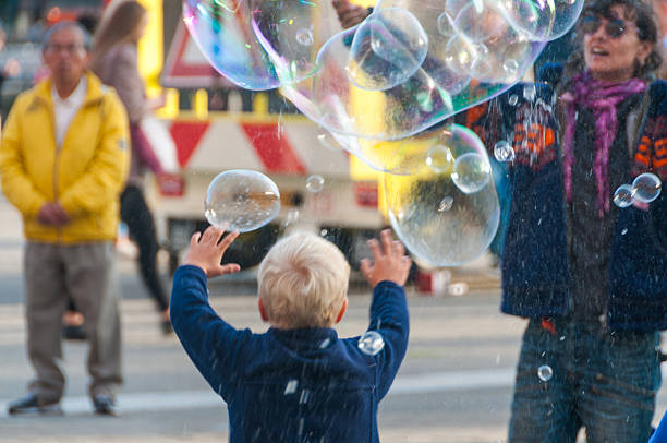 Amsterdam, Netherlands - September 28, 2015. Street scene, showing an artist creating a colourful display of soap bubbles near central station in Amsterdam. Spectators are watching an playing with the bubbles.