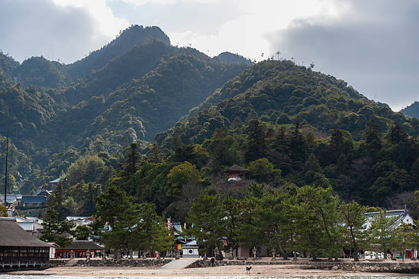 Hatsukaichi, Japan - December 31, 2019. Outdoor scene showing the beautiful mountain scenery of Miyajima island, with the Itsukushima Jinia Shrine in the foreground.