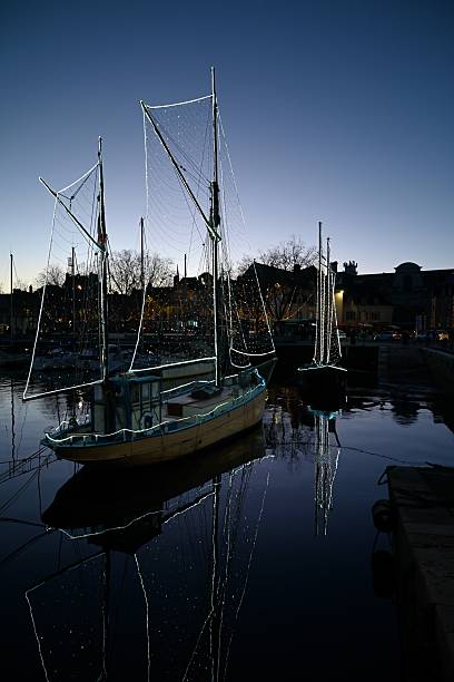 Vannes, France, december 10, 2025 : Decorated old sailing ships moored along the Gambetta quay in Vannes in the evening during the Christmas holidays